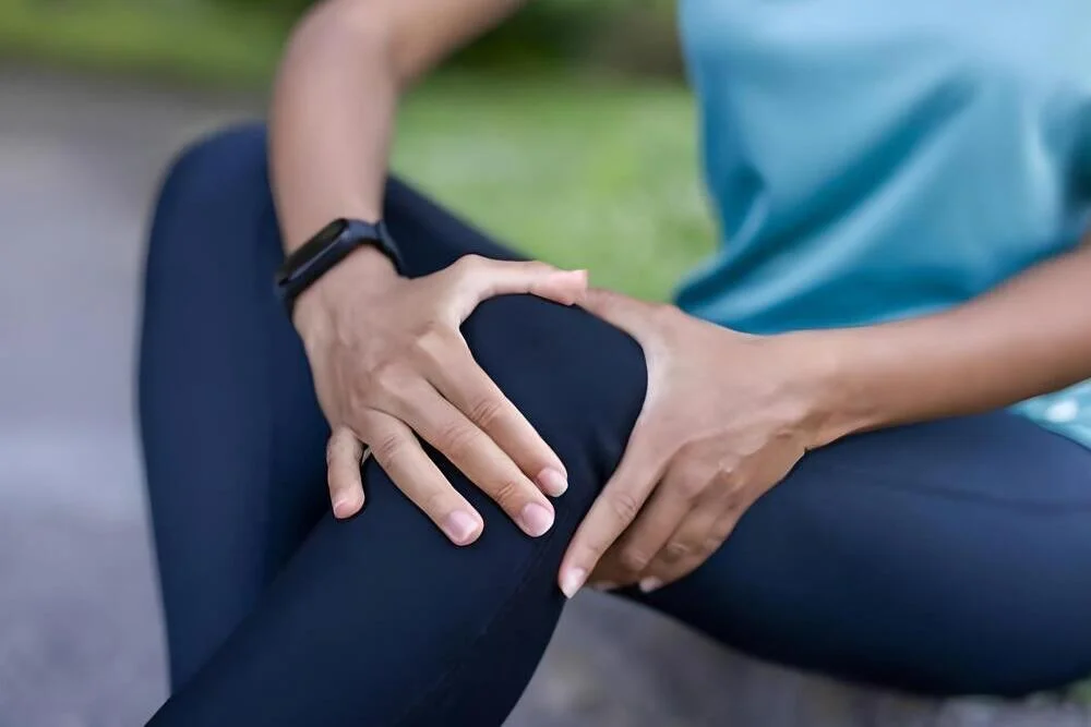 persona sentada en acera con dolor de rodilla