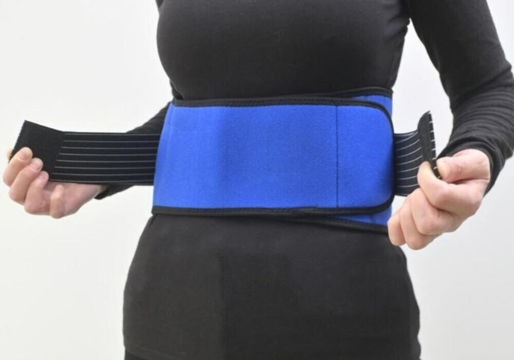 mujer ajustando faja de compresion azul sobre ropa deportiva