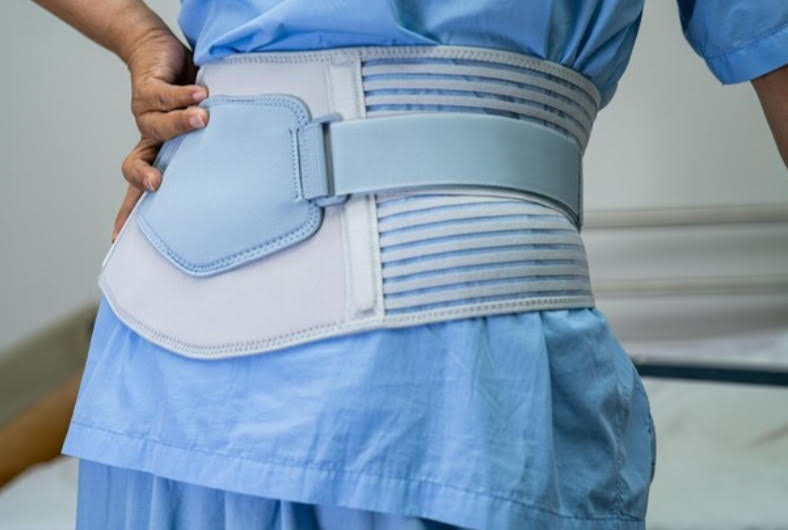 soporte lumbar de color celeste colocado sobre ropa medica