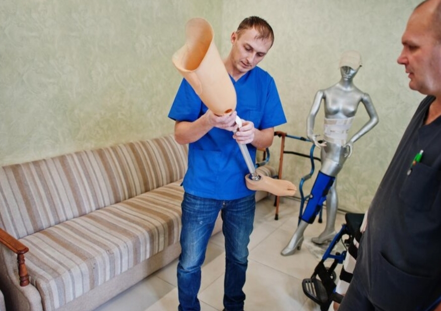 especialista sosteniendo protesis de pierna mientras paciente observa en centro de rehabilitacion